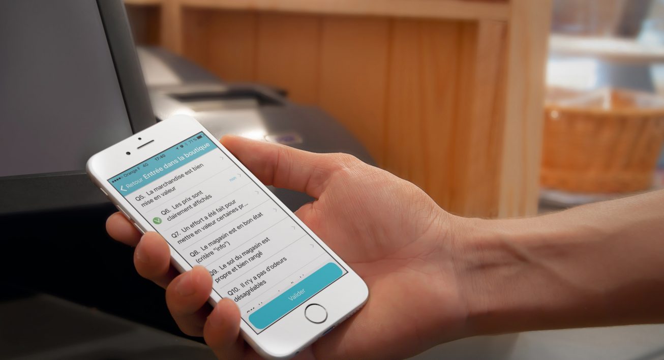 Photographie d'une main tenant un smartphone qui affiche l'application mobile Smice