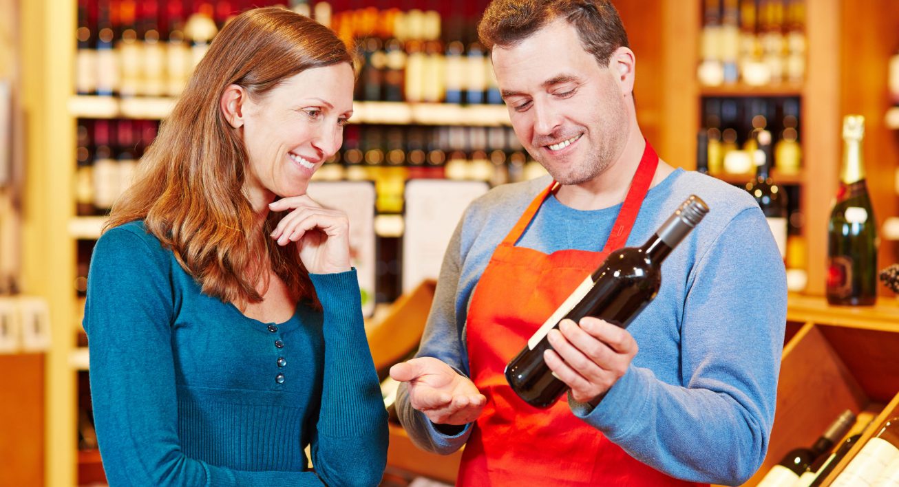 Photographie d'un sommelier qui conseille une bouteille de vin à une cliente